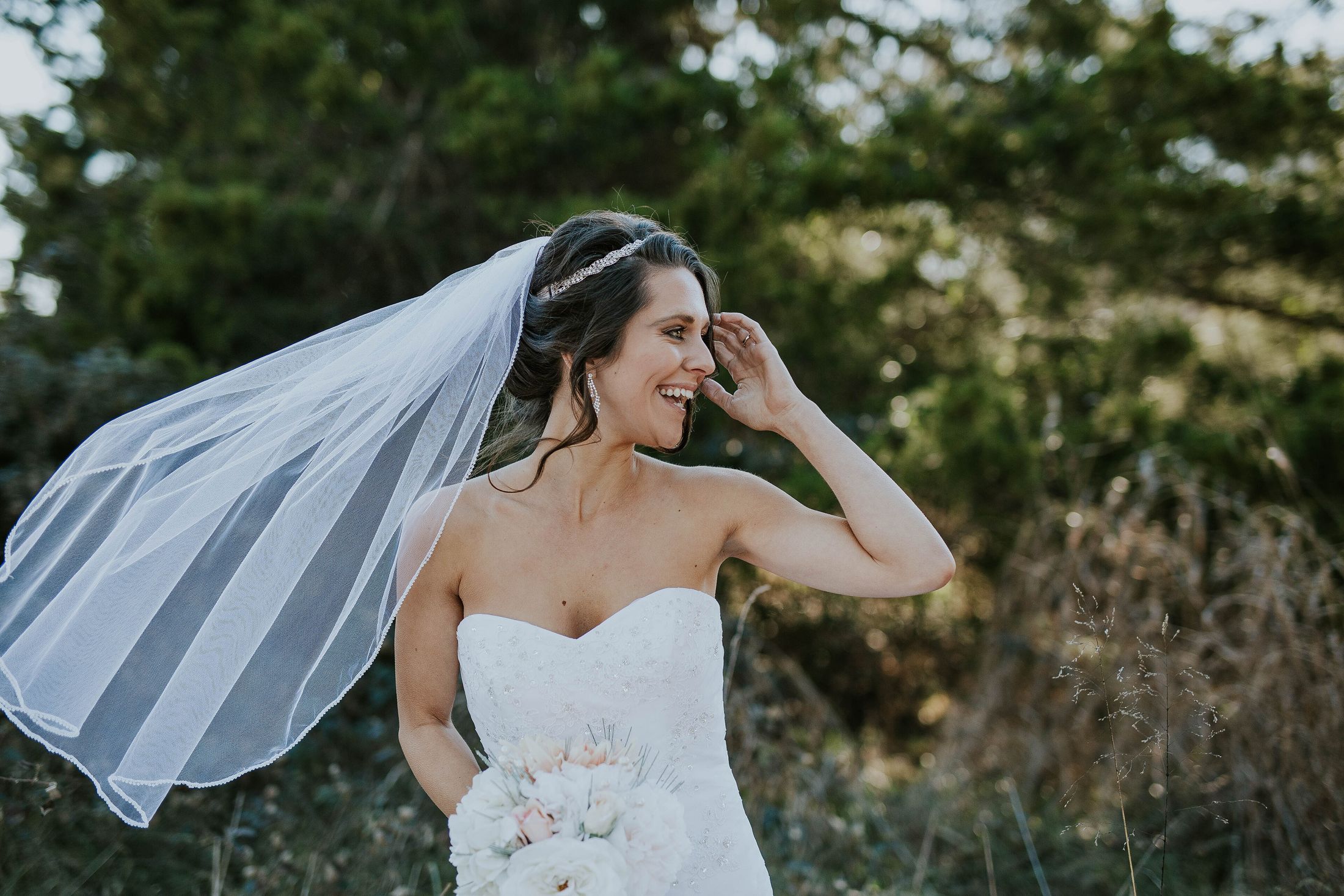 A laughing bride with her veil caught by the wind